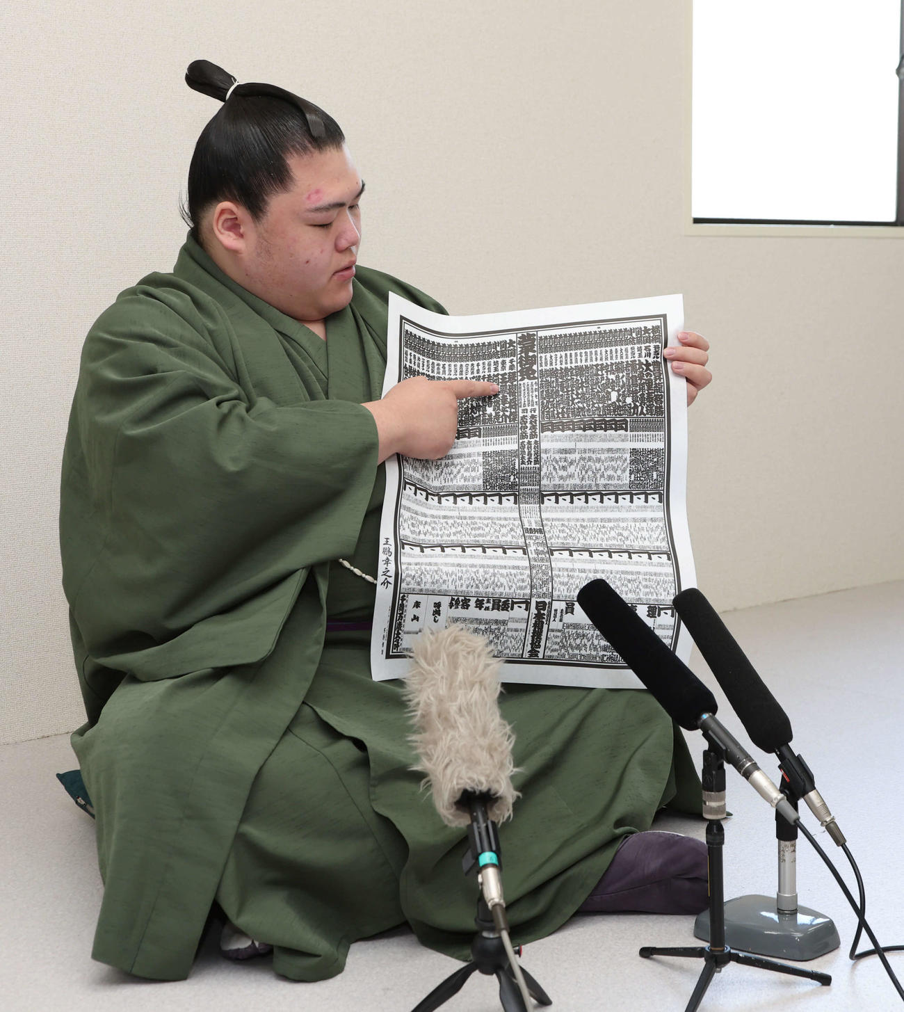 春場所で新関脇に昇進した王鵬はしこ名が載った番付を指さす（撮影・西尾就之）