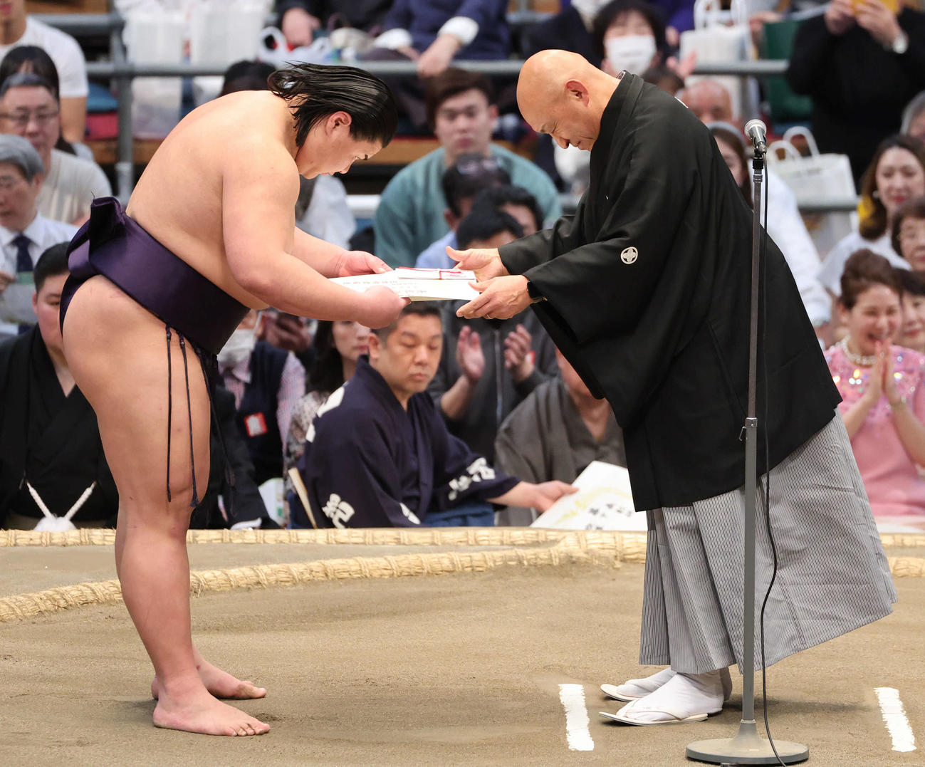 十両優勝の草野は表彰を粂川親方（元小結琴稲妻）から受ける（撮影・西尾就之）