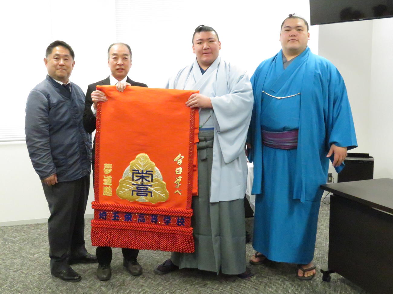 母校の埼玉栄高から化粧まわしを贈呈された夢道鵬（右から2人目）。右端は兄の王鵬、左から埼玉栄高の山田監督、勅使河原校長
