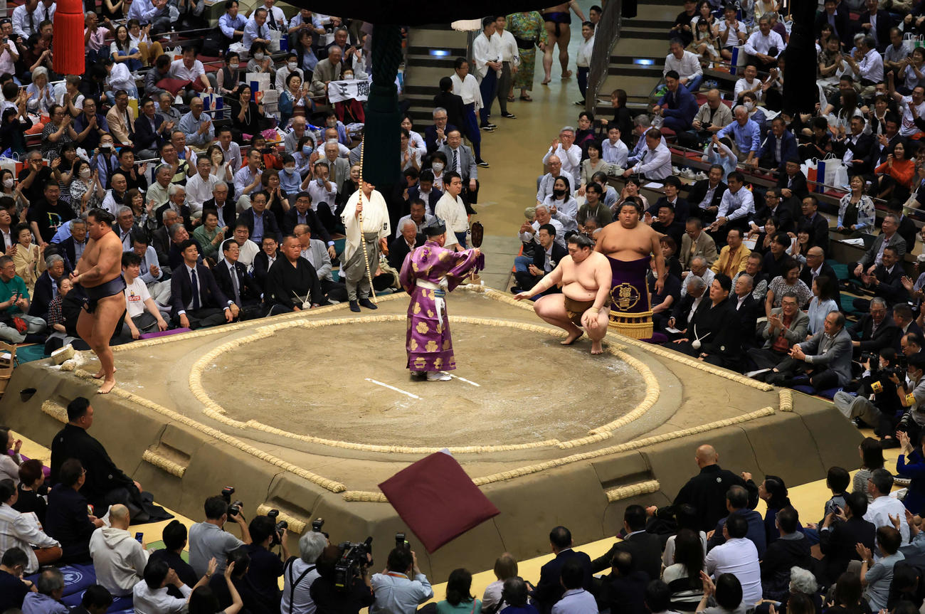 豊昇龍（左）をはたき込みで王鵬が破り、ザブトンが飛ぶ会場（撮影・浅見桂子）