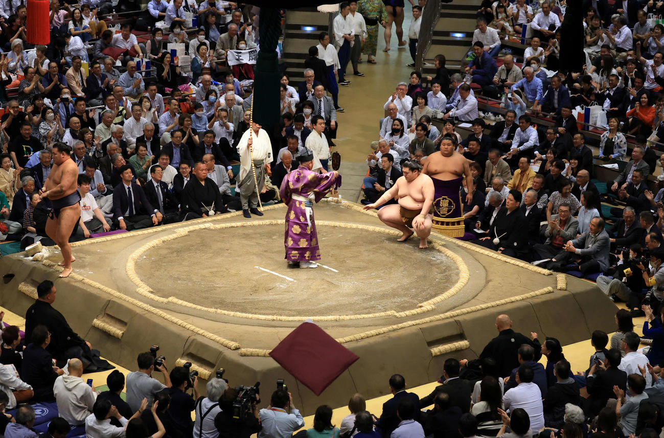 豊昇龍（左）をはたき込みで王鵬が破り、ザブトンが飛ぶ会場（撮影・浅見桂子）