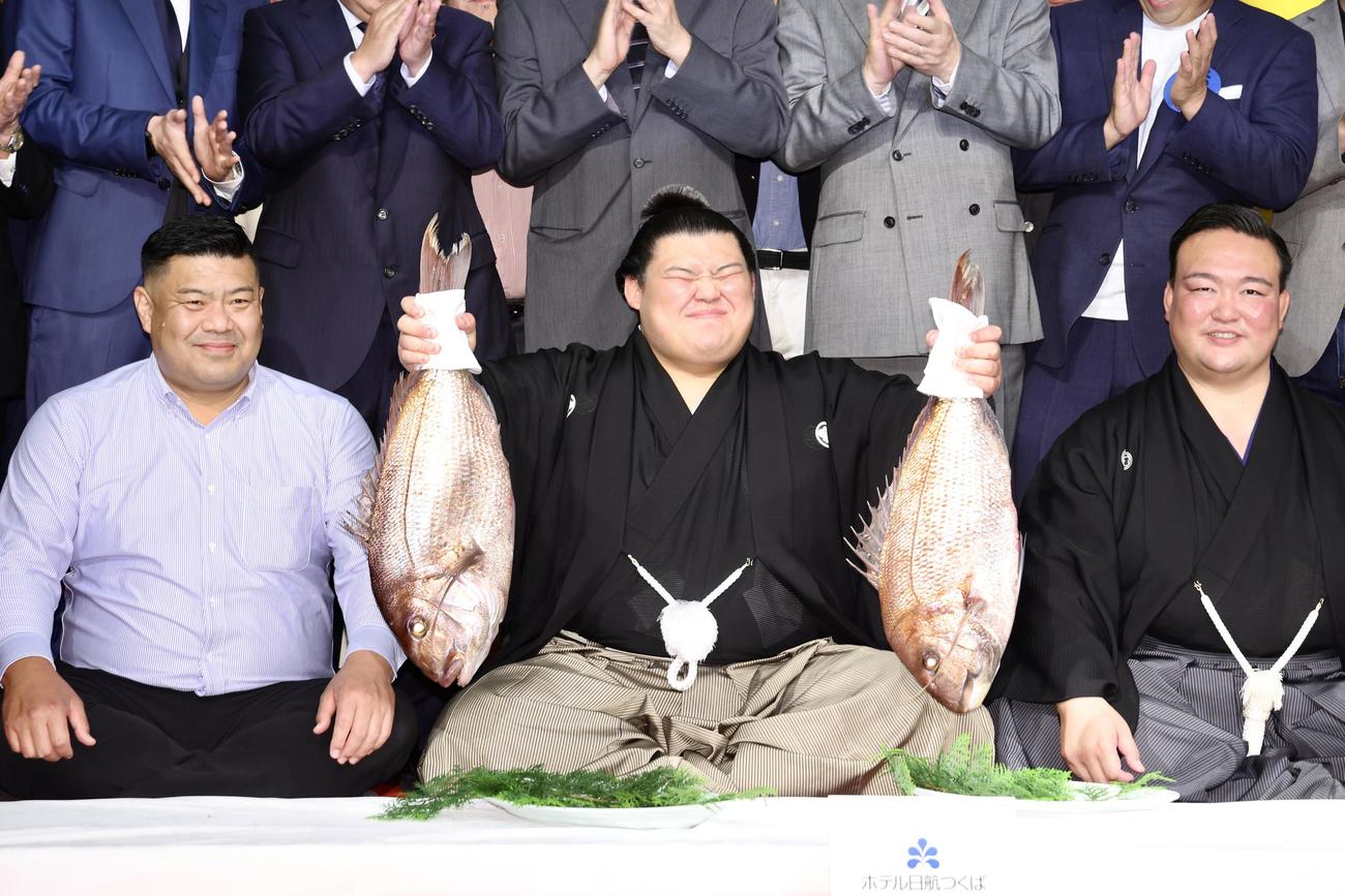 鯛持ちで笑顔を見せる大の里（中央）。左は父・中村知幸さん、右は二所ノ関親方（撮影・河田真司）