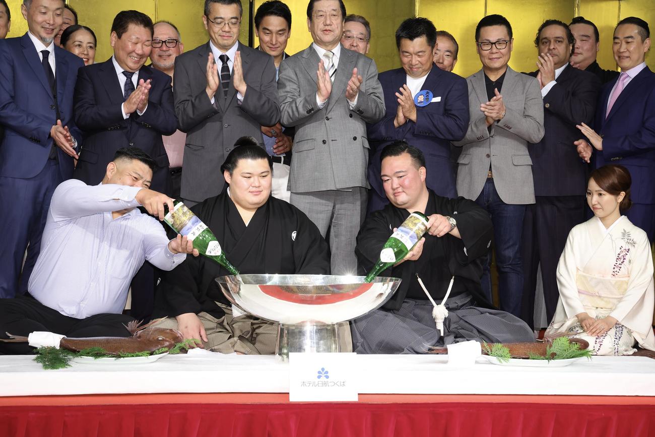 父・中村知幸さん（前列左）、二所ノ関親方（前列右から2人目）にお酒をついでもらう大の里（中央）（撮影・河田真司）