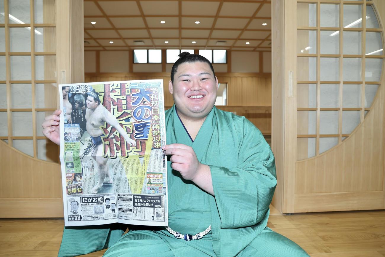 大相撲夏場所13日目の本紙面を手に笑顔で写真に納まる大の里（撮影・河田真司）