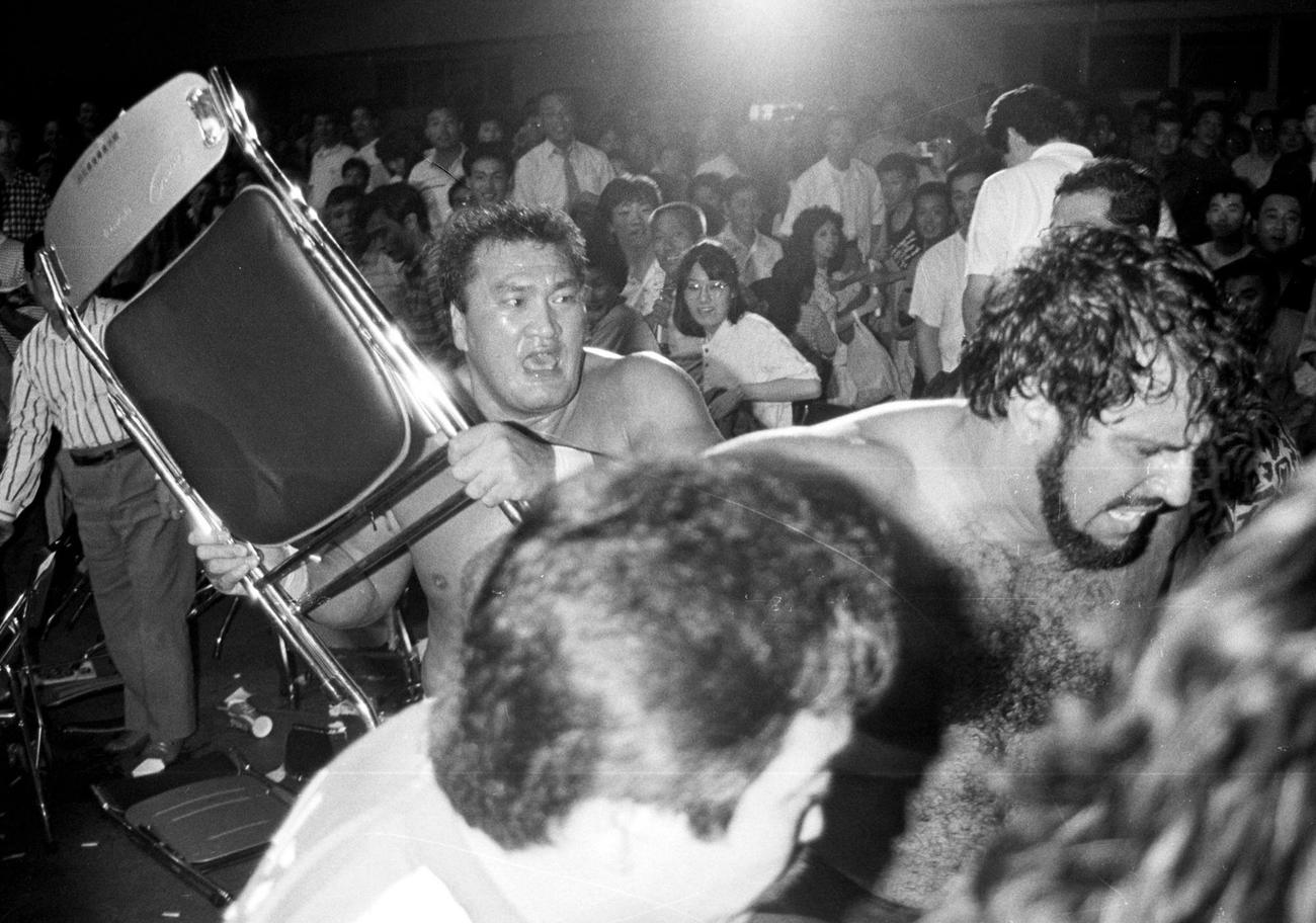 全日本金沢大会　リング場外でタイガー・ジェット・シン（右）にイスを使って攻撃する輪島＝1987年6月1日　ネガ番号プロレス2212－3－6