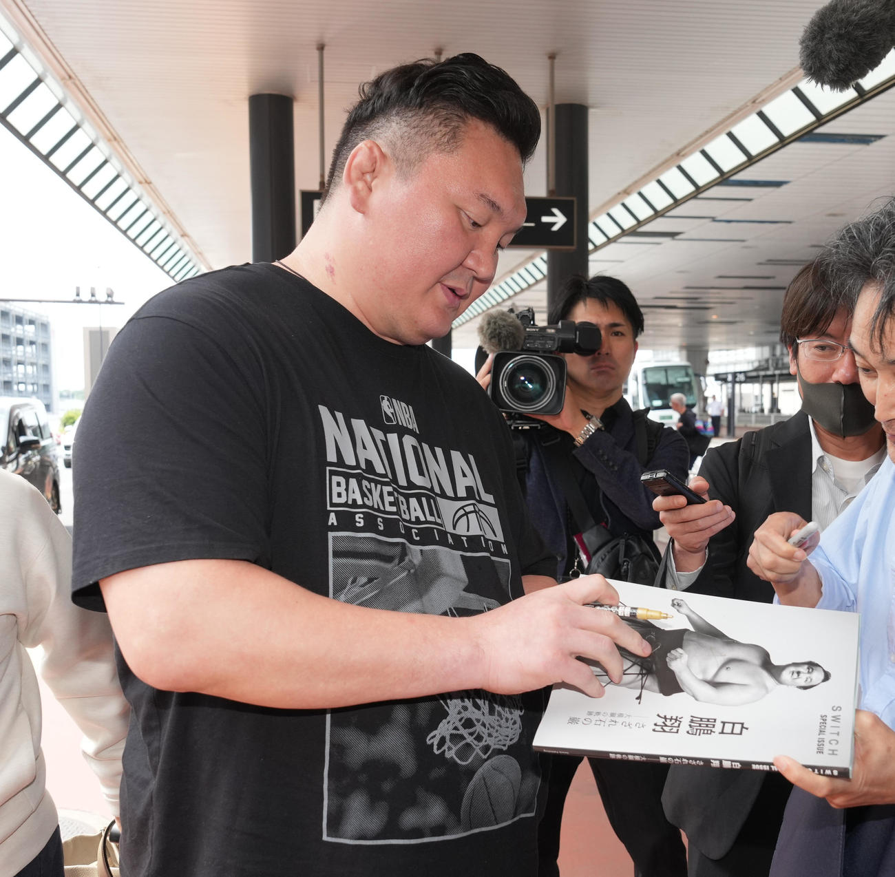 モンゴルから帰国した宮城野親方は待ち構えた相撲ファンからサインの要望に応える（撮影・小沢裕）