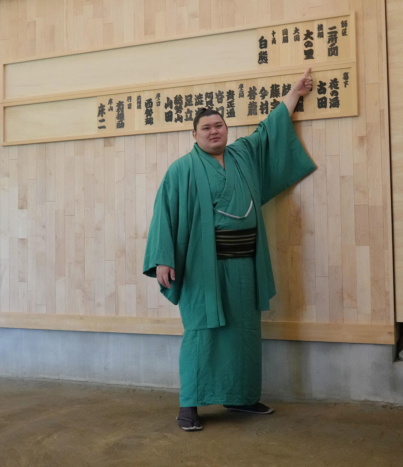 会見を終え稽古場の自身の名札を指さす横綱大の里（撮影・森本幸一）
