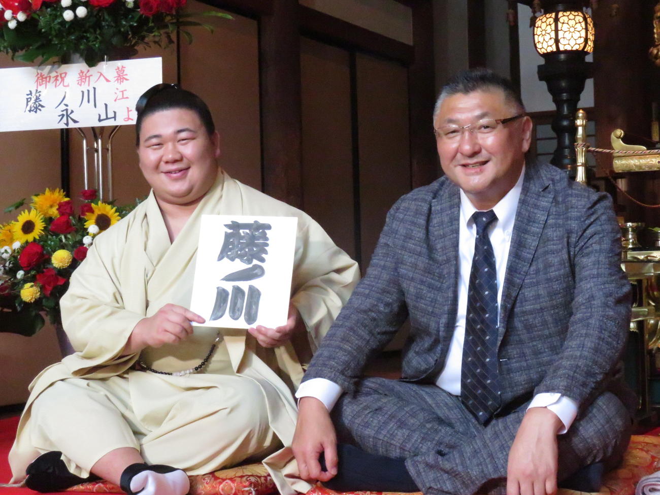 師匠の伊勢ノ海親方（右）とともに新入幕会見に臨んだ若碇改め藤ノ川は、しこ名が書かれた色紙を手に笑顔を見せた