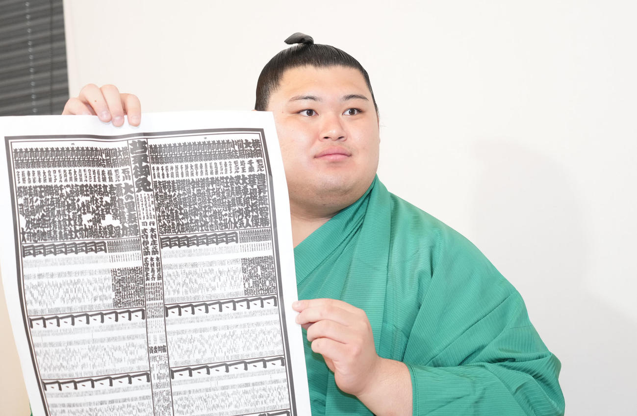 番付表を手に会見の冒頭、撮影に応じる横綱大の里（撮影・森本幸一）