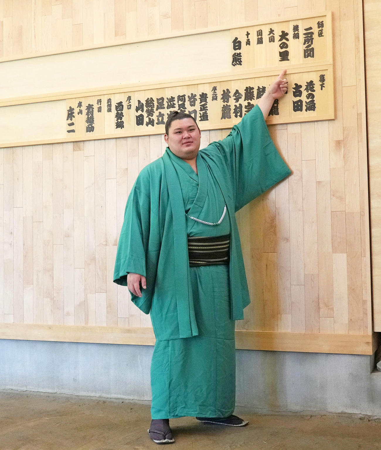 会見を終え稽古場の自身の名札を指さす横綱大の里（撮影・森本幸一）