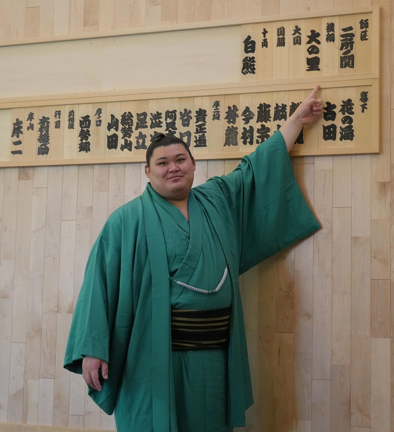 会見を終え稽古場の自身の名札を指さす横綱大の里（撮影・森本幸一）