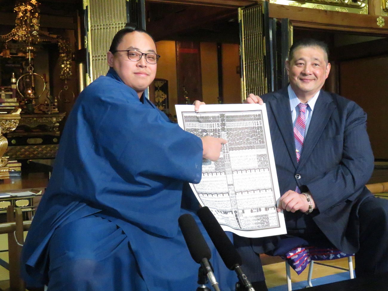 師匠の佐渡ケ嶽親方（右）とともに新入幕会見に臨んだ琴栄峰は、新番付の自身のしこ名を指さして笑顔を見せた