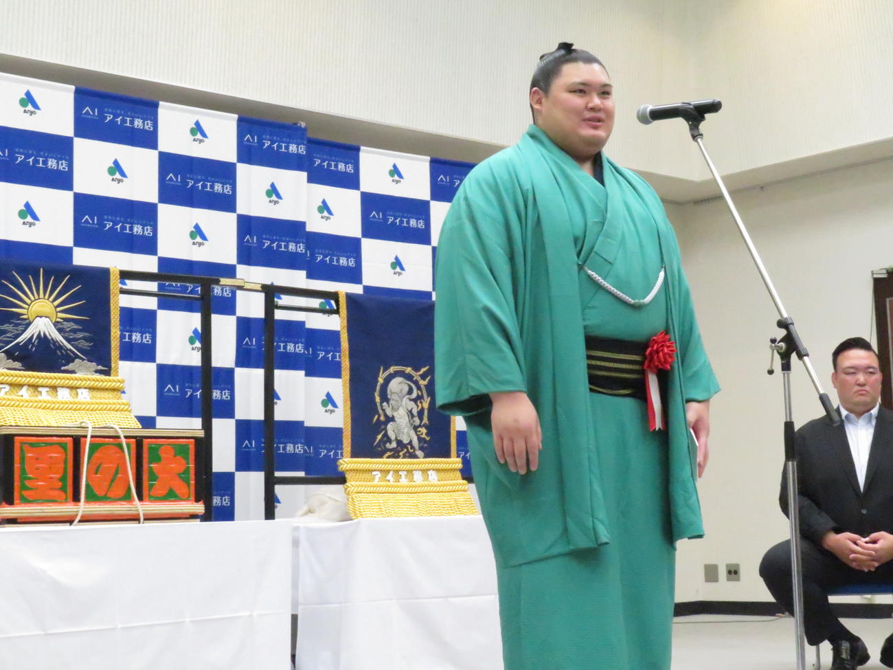 三つぞろえの化粧まわしの贈呈式で、感謝を述べる大の里。右は師匠の二所ノ関親方