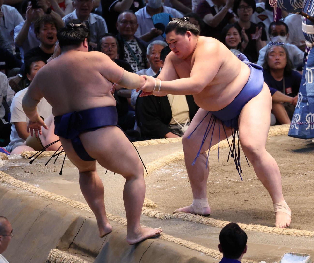 大の里（右）は押し出しで阿炎を下し、土俵下に落ちそうになった相手の腕をつかんで支える（撮影・西尾就之）