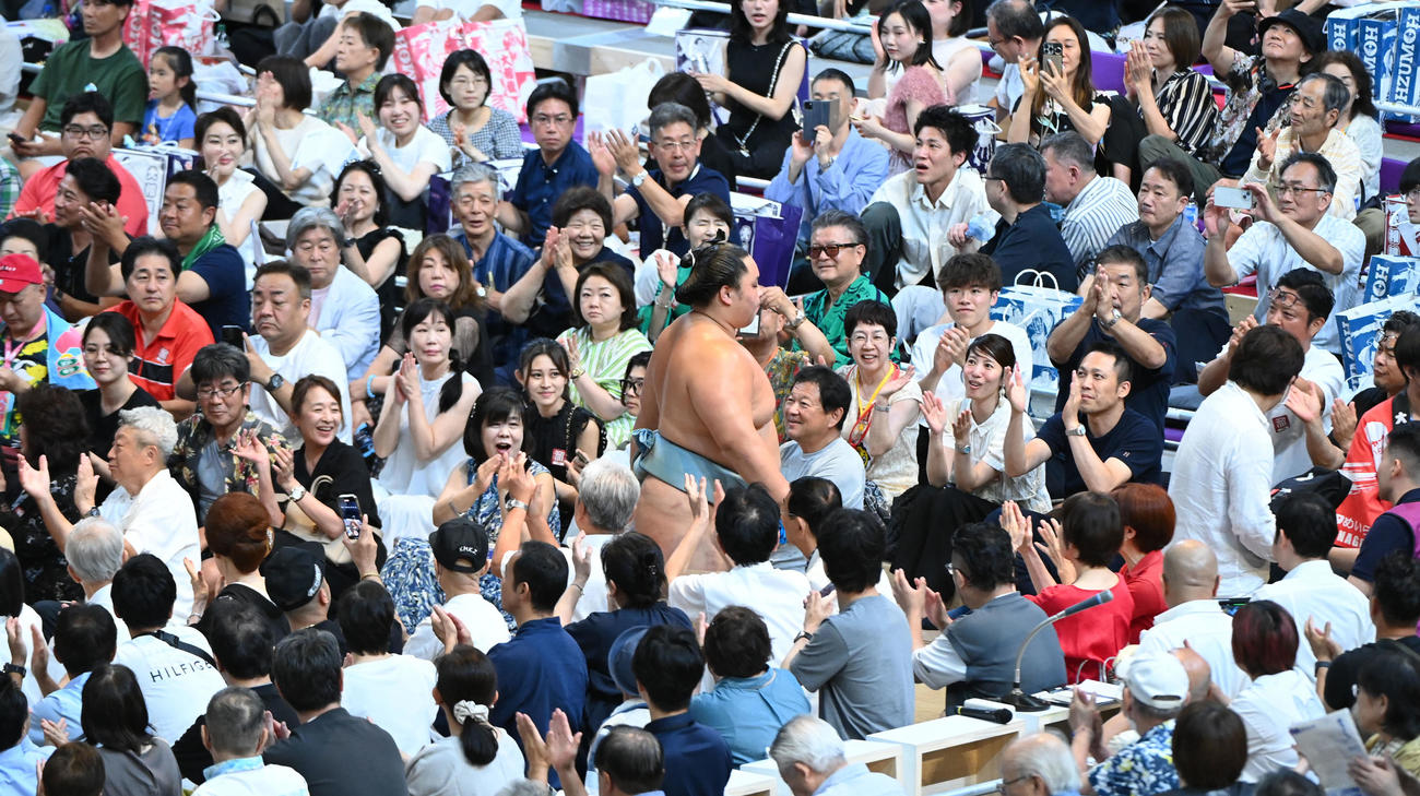 琴勝峰（中央）は安青錦を突き落としで破り観客の拍手の中、花道を引き揚げる（撮影・森本幸一）
