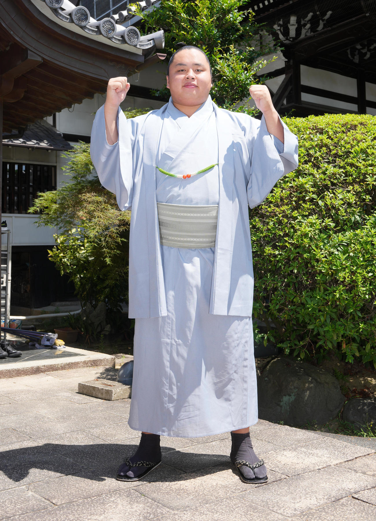 優勝一夜明け会見を終え宿舎を背にガッツポーズする琴勝峰（撮影・小沢裕）