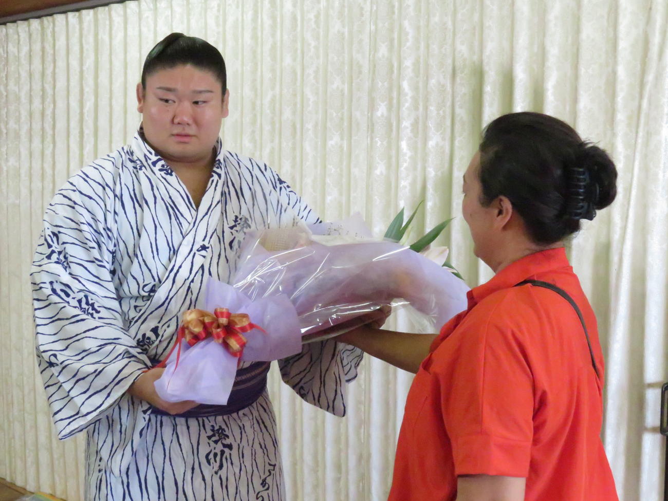 部屋宿舎での新十両会見後、部屋関係者から花束を受け取った西ノ龍