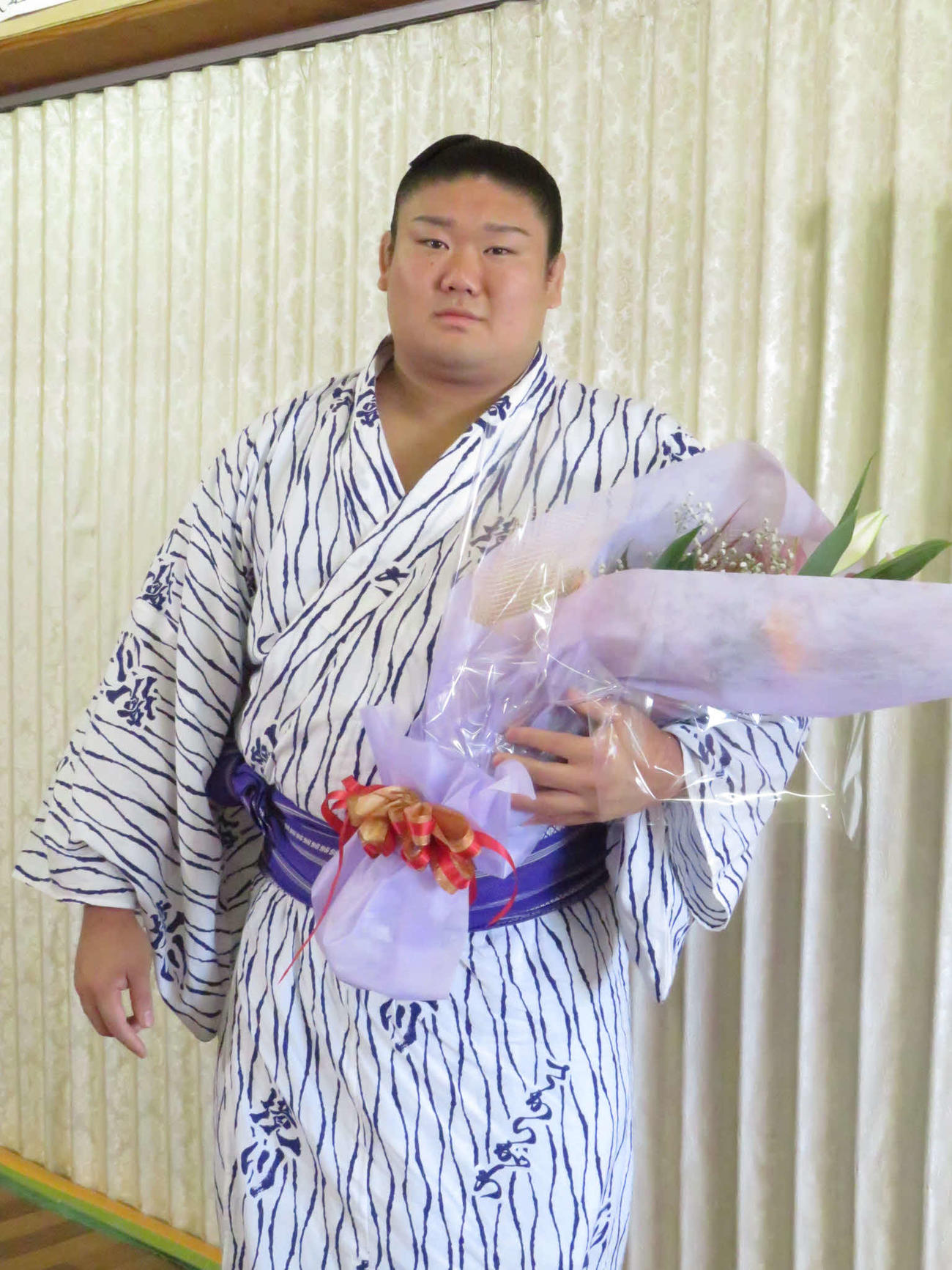 部屋宿舎での新十両会見後、受け取った花束を手にする西ノ龍