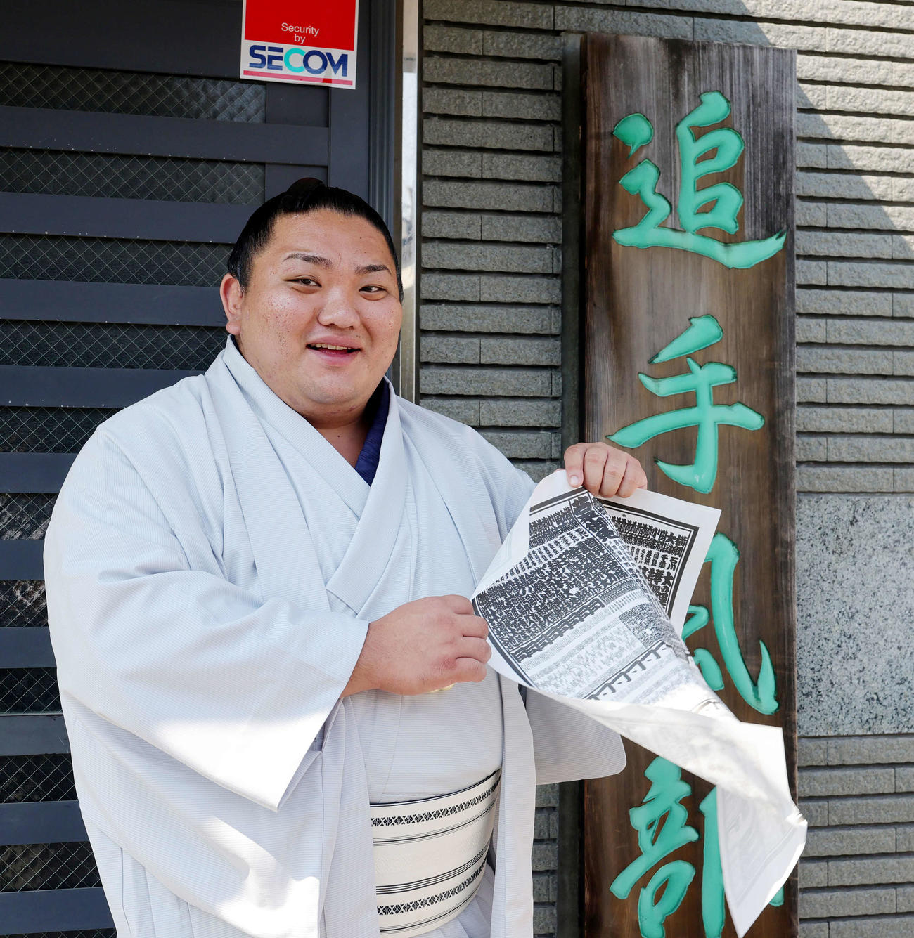 新入幕を果たした日翔志は、屋外撮影で風が強く番付表がめくれ、「これ、無理でしょ」と苦笑い（撮影・野上伸悟）