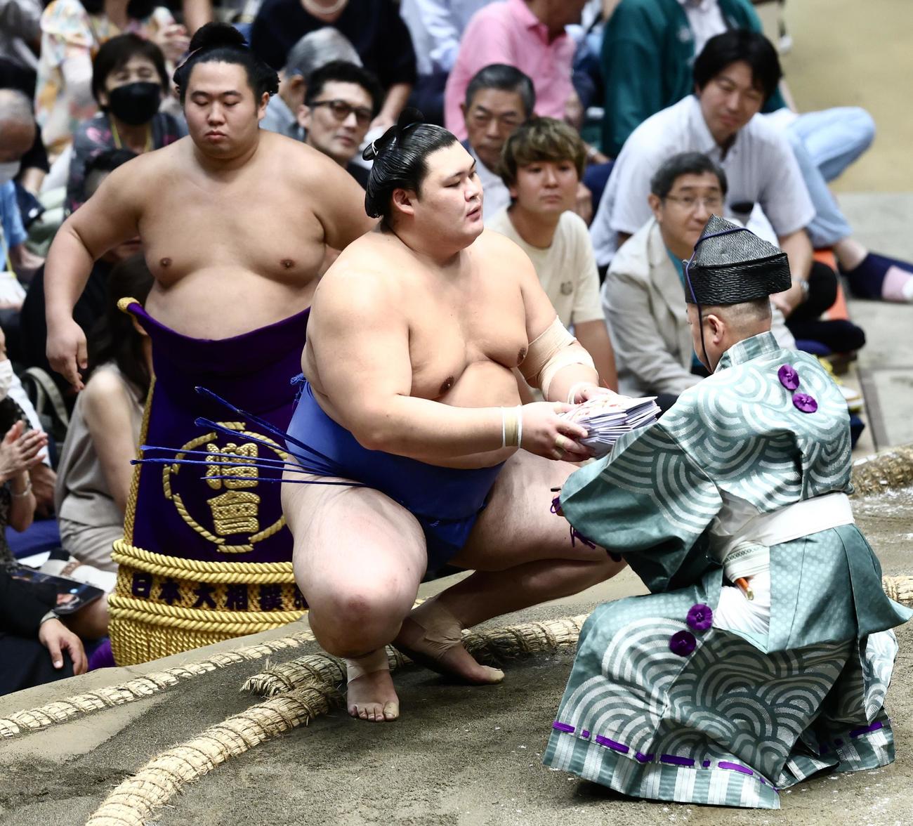 阿炎を押し倒しで破り、懸賞金の束を手にする大の里（撮影・河田真司）