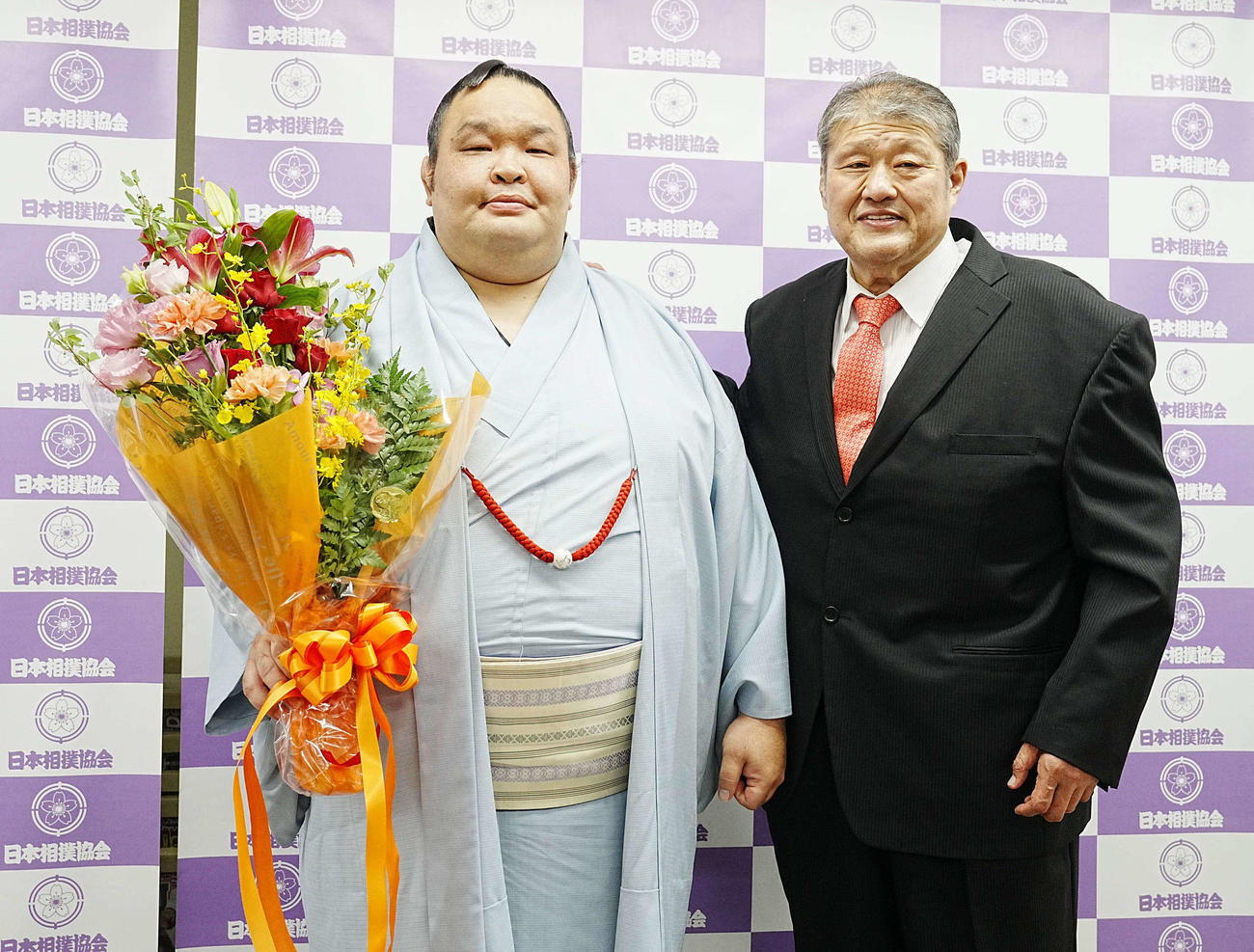 引退会見で花束を手に記念撮影に臨む水戸龍。右は師匠の錦戸親方（撮影・小沢裕）