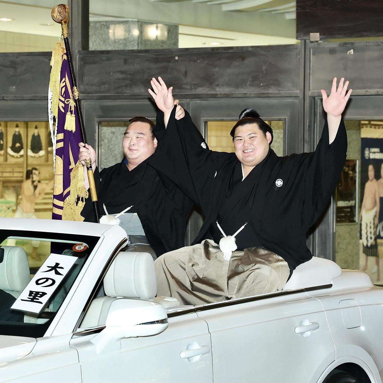 パレード車からファンの声援に応える大の里（右）と旗持ちの白熊（撮影・河田真司）