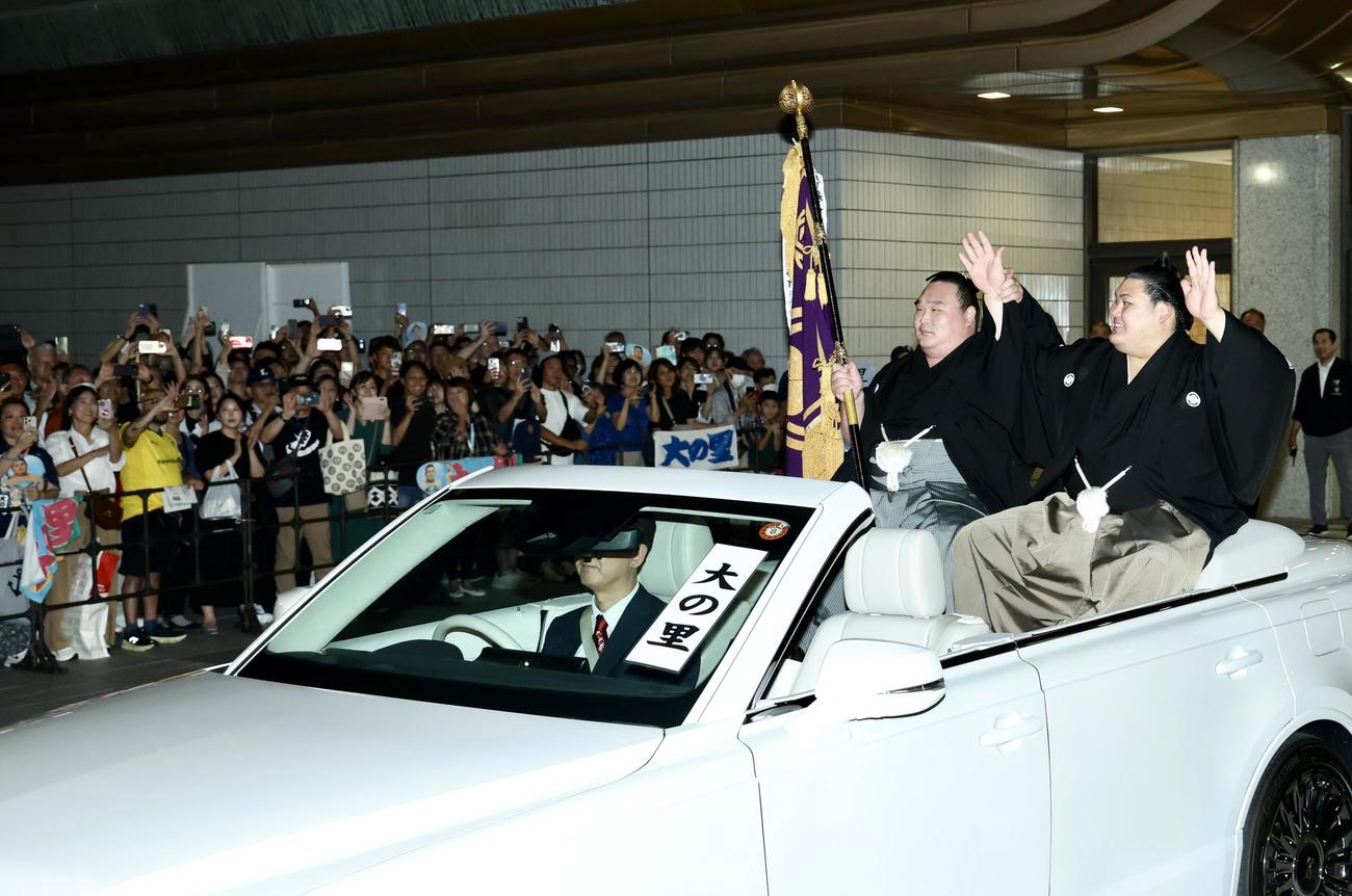 パレード車からファンの声援に応えながら移動する大の里（右）と旗持ちの白熊（撮影・河田真司）