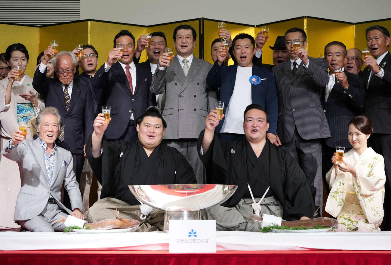 千秋楽パーティーで関係者の祝福を受けながらビールで乾杯する大の里。右は師匠の二所ノ関親方（撮影・小沢裕）