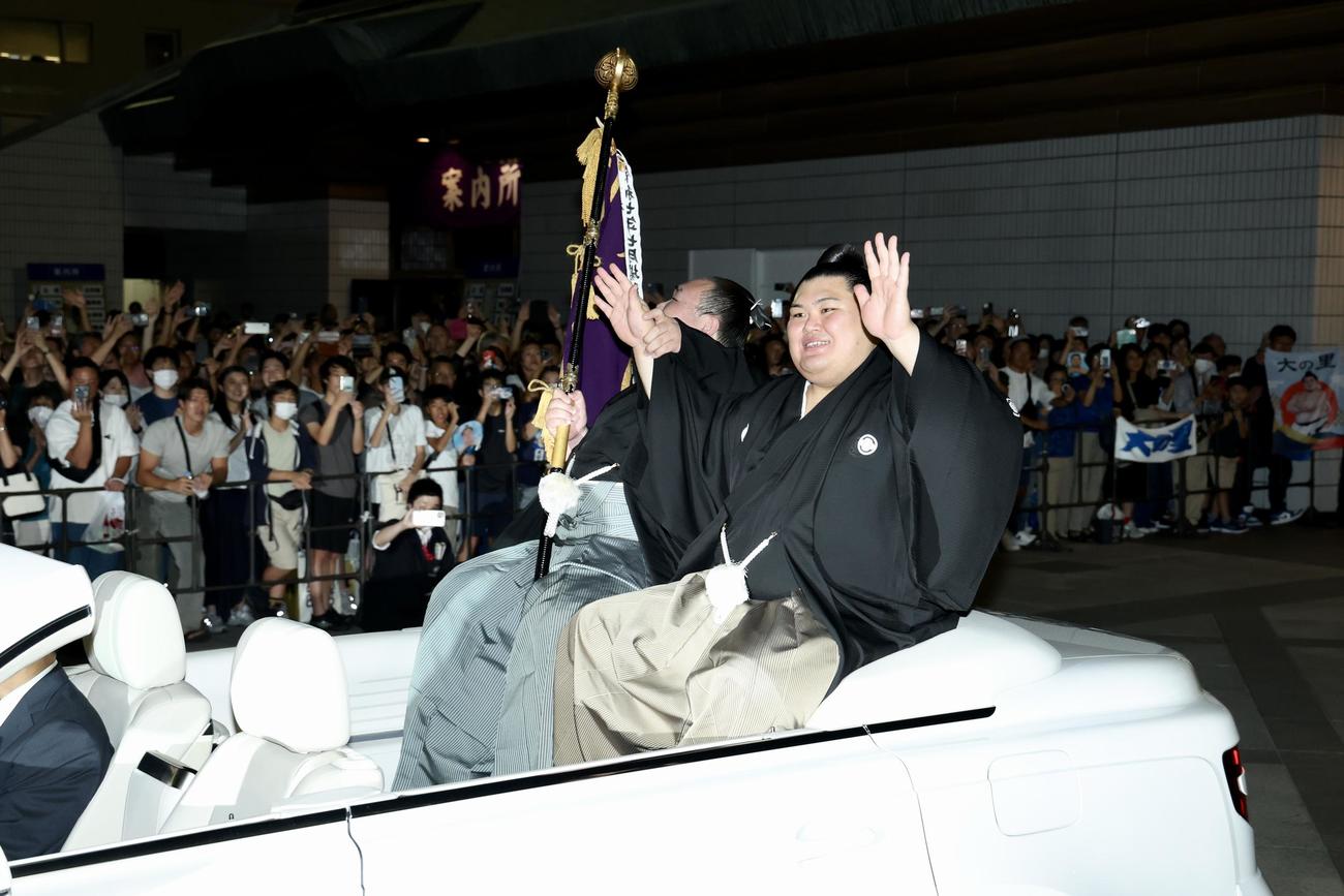 パレード車からファンの声援に応えながら移動する大の里（右）と旗持ちの白熊（撮影・河田真司）