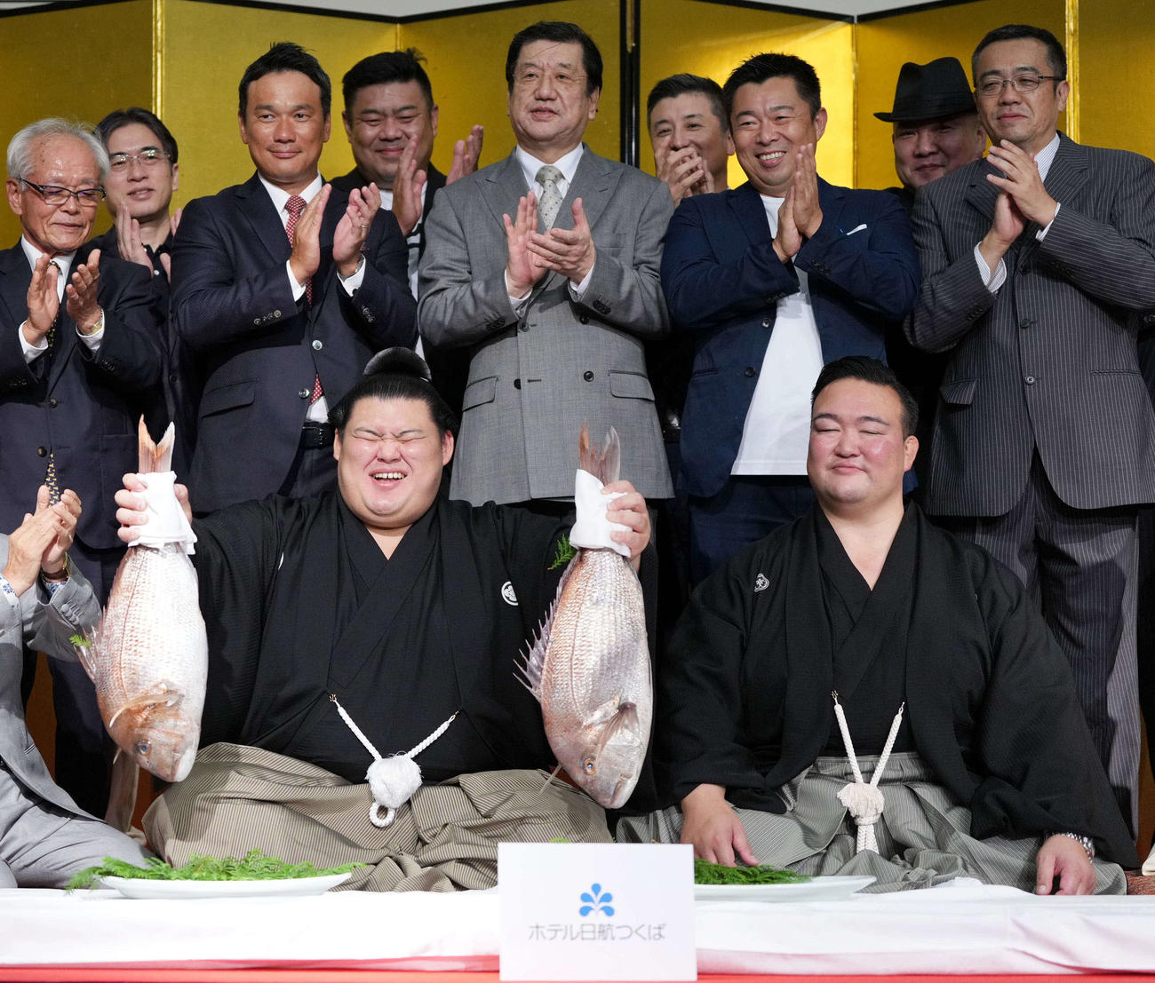 千秋楽パーティーで関係者の祝福を受けながらお祝いのタイを持つ大の里。右は師匠の二所ノ関親方（撮影・小沢裕）