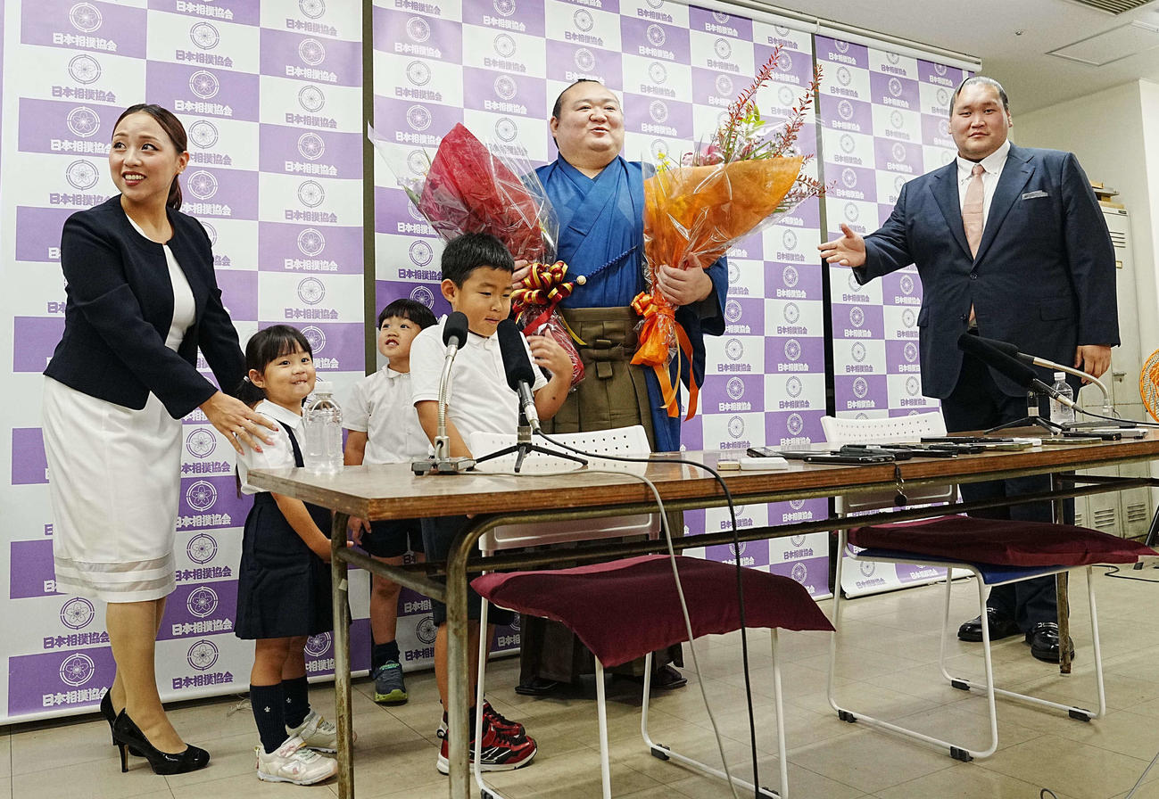 引退会見を終え家族から花束を贈呈される宝富士（中央）。左から英莉乃夫人、長女七凪（なな）ちゃん、次男凜丞（りんのすけ）くん、長男慶丞（けいのすけ）くん、右は師匠の伊勢ケ浜親方（撮影・小沢裕）