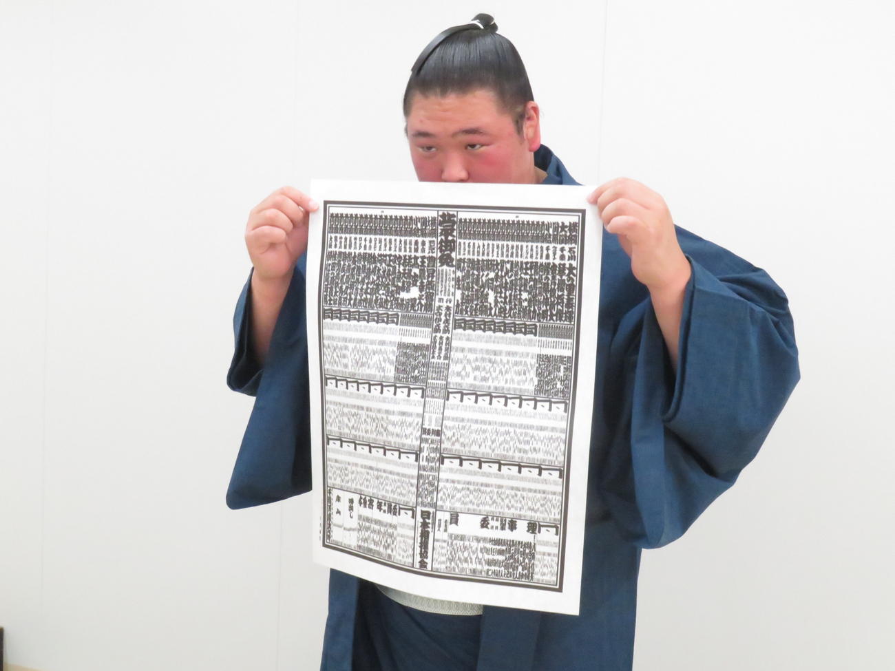 新入幕会見後、少し照れた様子で番付に顔を半分隠して写真撮影に臨んだ欧勝海