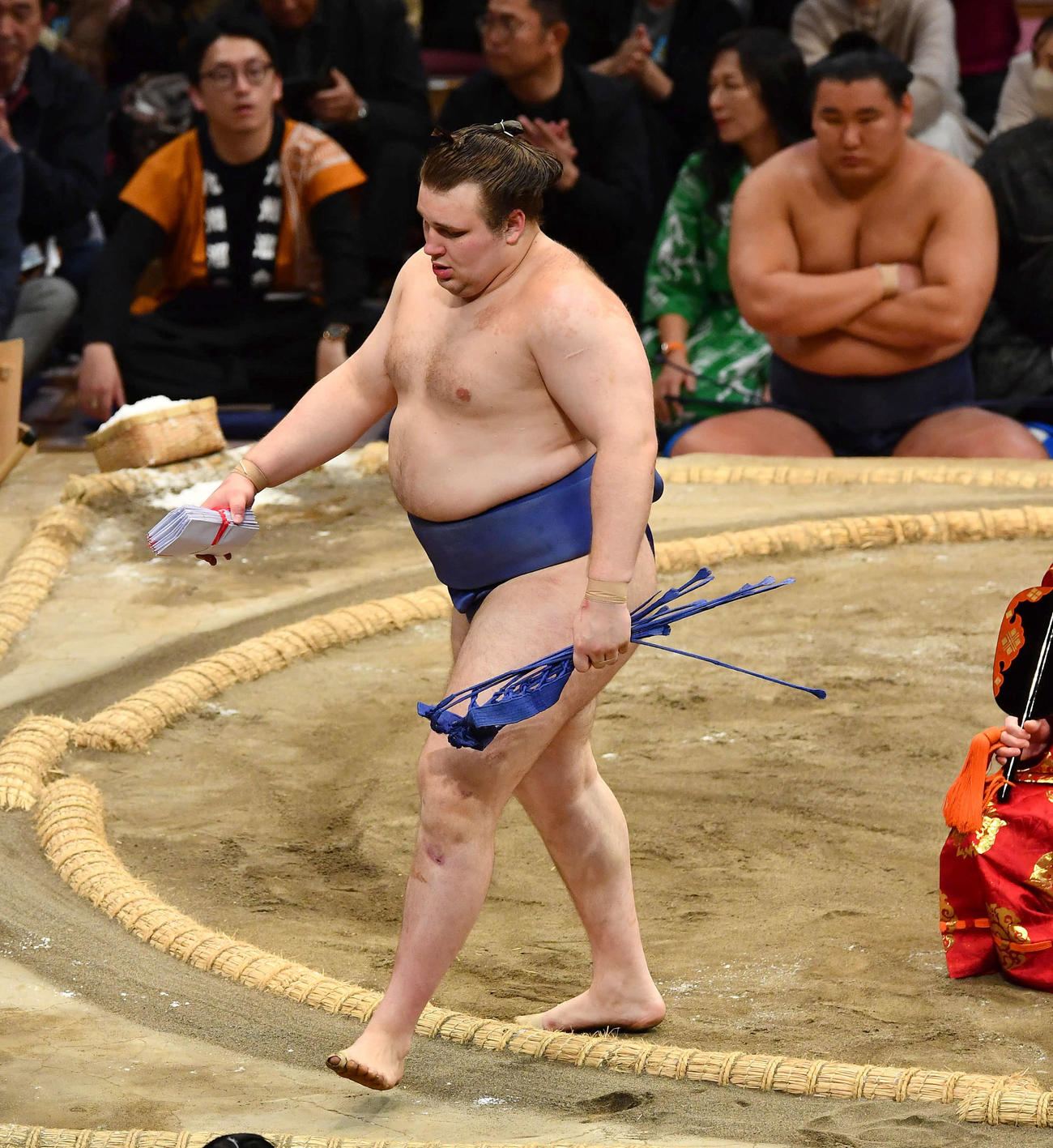 平戸海を寄り倒しで下し、懸賞金の束を手に土俵を下りる安青錦。右奥は豊昇龍（撮影・岩下翔太）
