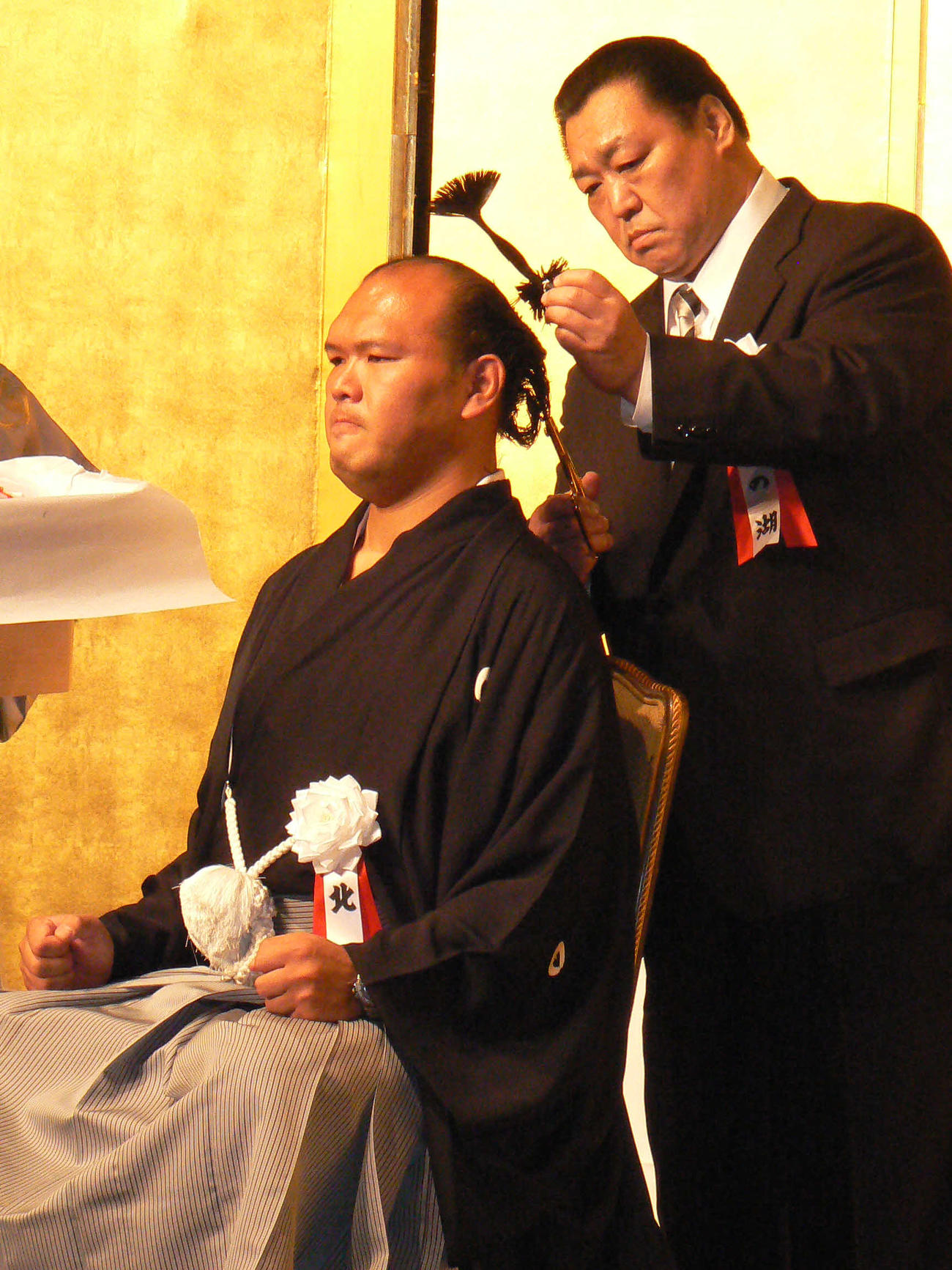 北の湖親方（元横綱・北の湖）にはさみを入れられる小野川親方（元前頭・北桜）（2010年10月1日撮影）