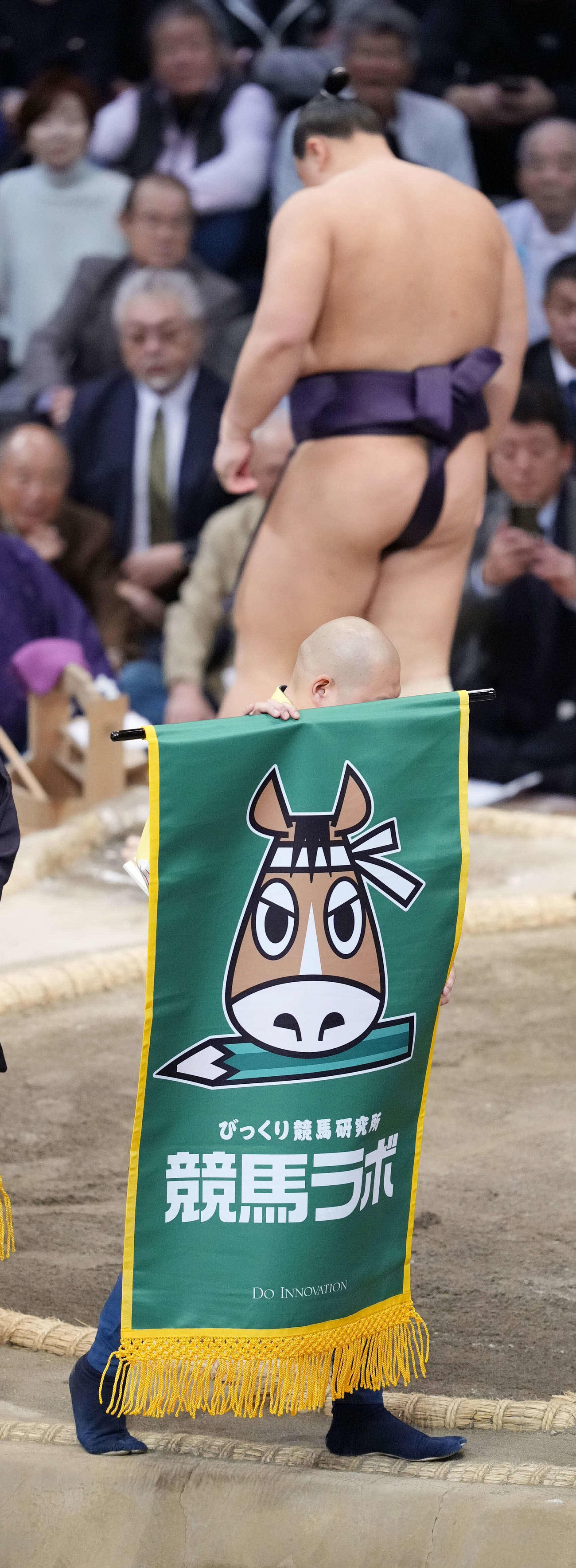 義ノ富士と高安の一番で土俵をまわる「競馬ラボ」の懸賞幕（撮影・小沢裕）