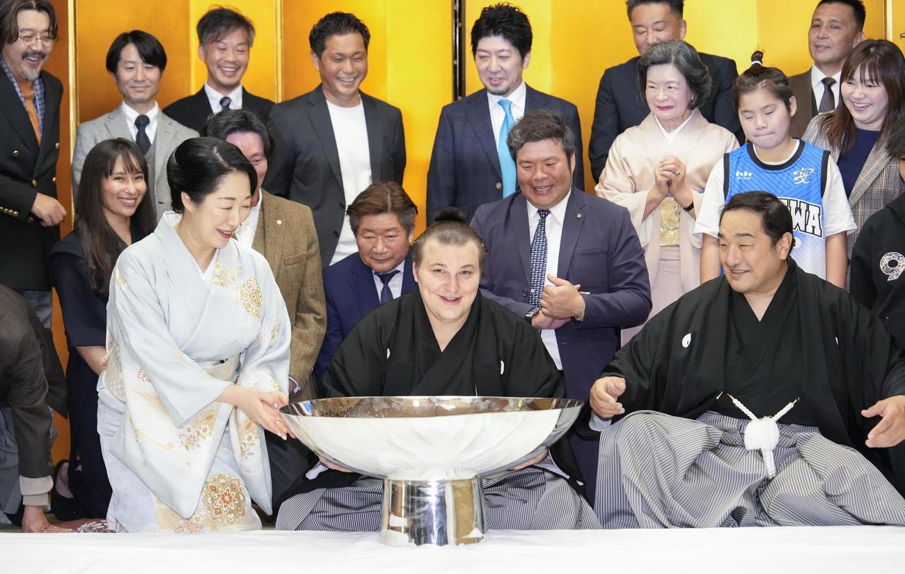 大相撲九州場所で初優勝を果たし、祝杯を手にする安青錦。右隣は師匠の安治川親方＝23日、福岡県久留米市(共同)