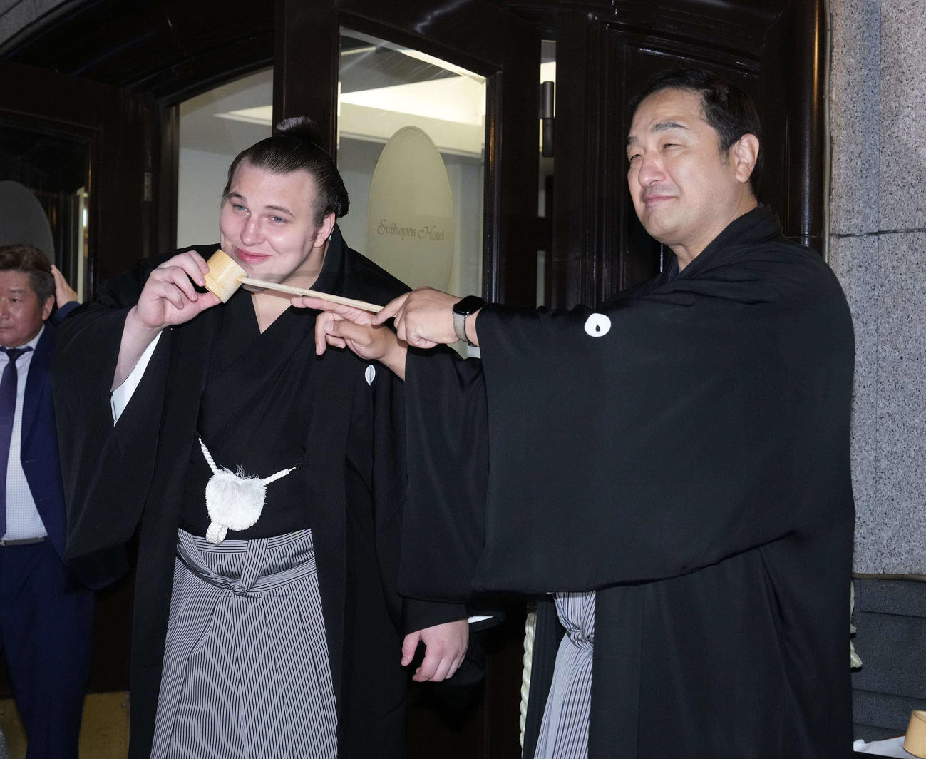 千秋楽パーティーで師匠の安治川親方（右）から水をつけてもらう安青錦（撮影・小沢裕）