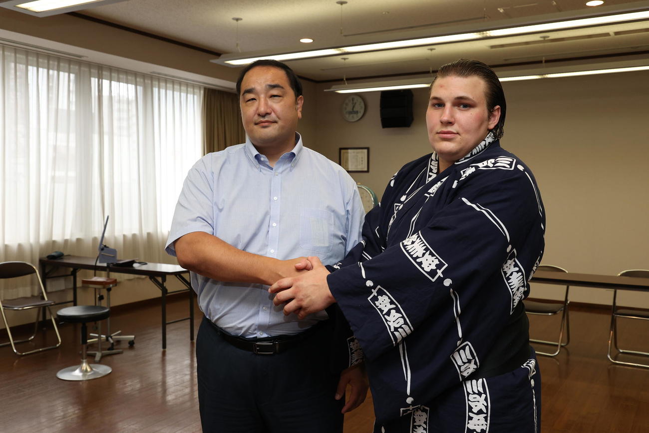 23年7月、大相撲新弟子検査で受検した安青錦（右）は、師匠の安治川親方と握手