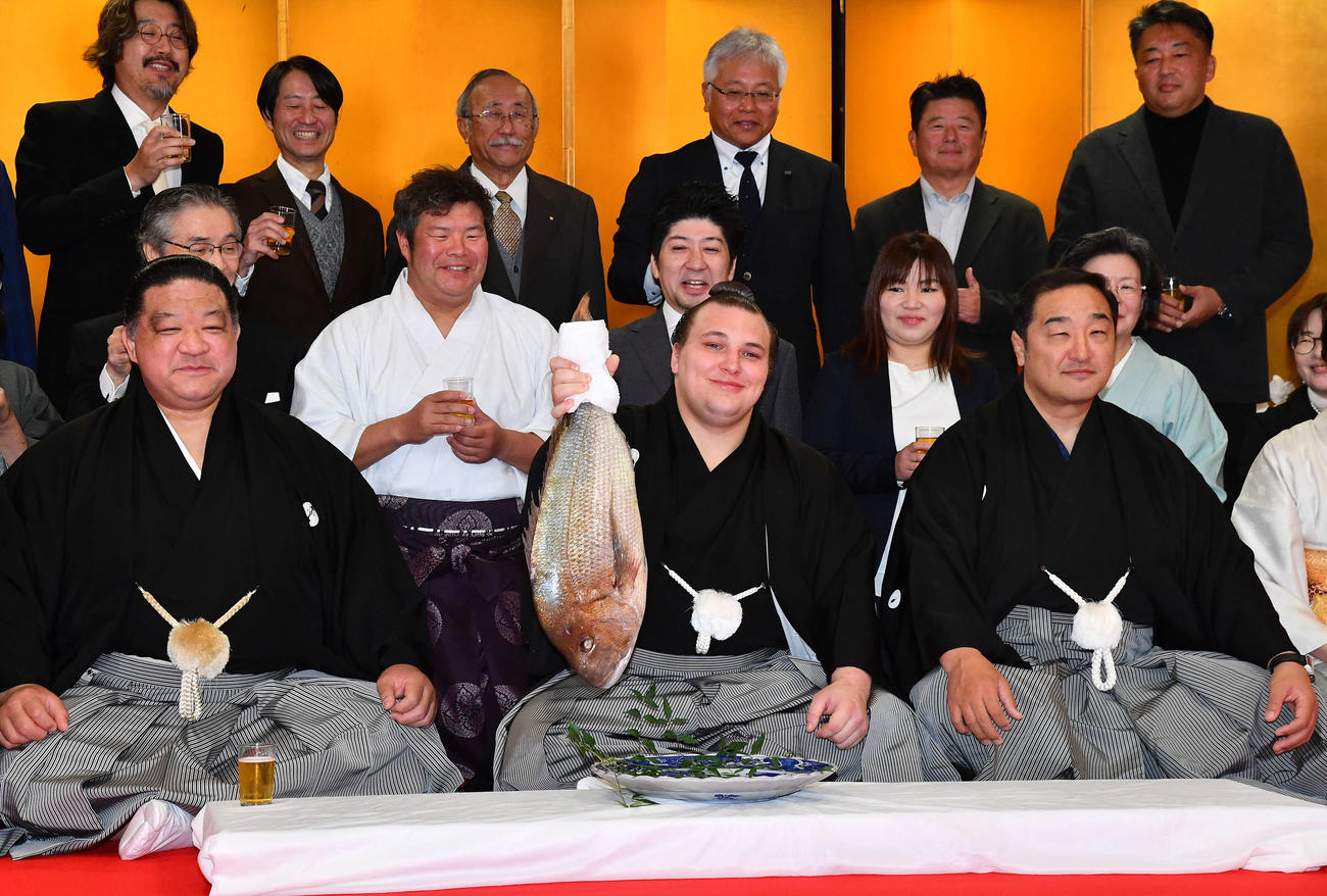 大関昇進の伝達式を終え、笑顔でタイを持つ安青錦（中央）。右は安治川親方（元関脇安美錦）、左は使者を務めた浅香山親方（元大関魁皇）（撮影・岩下翔太）