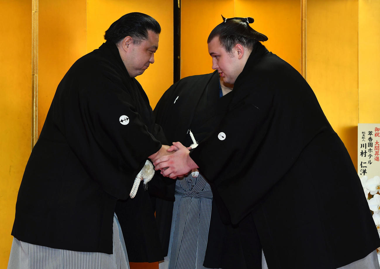 大関昇進の伝達式を終え、使者を務めた浅香山親方（左、元大関魁皇）と握手を交わす安青錦（撮影・岩下翔太）
