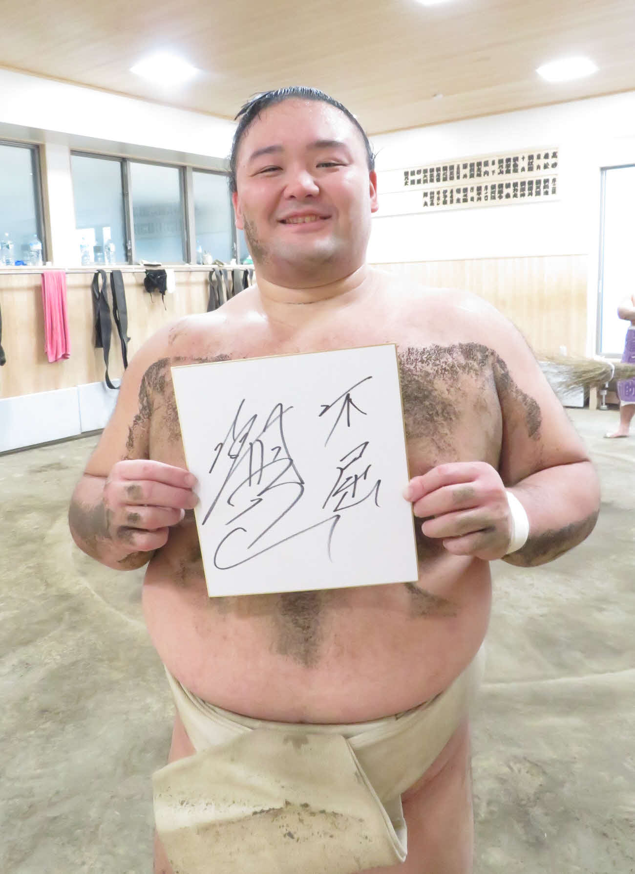 色紙に「不屈」と来年の意気込みを書き、笑顔を見せた朝乃山