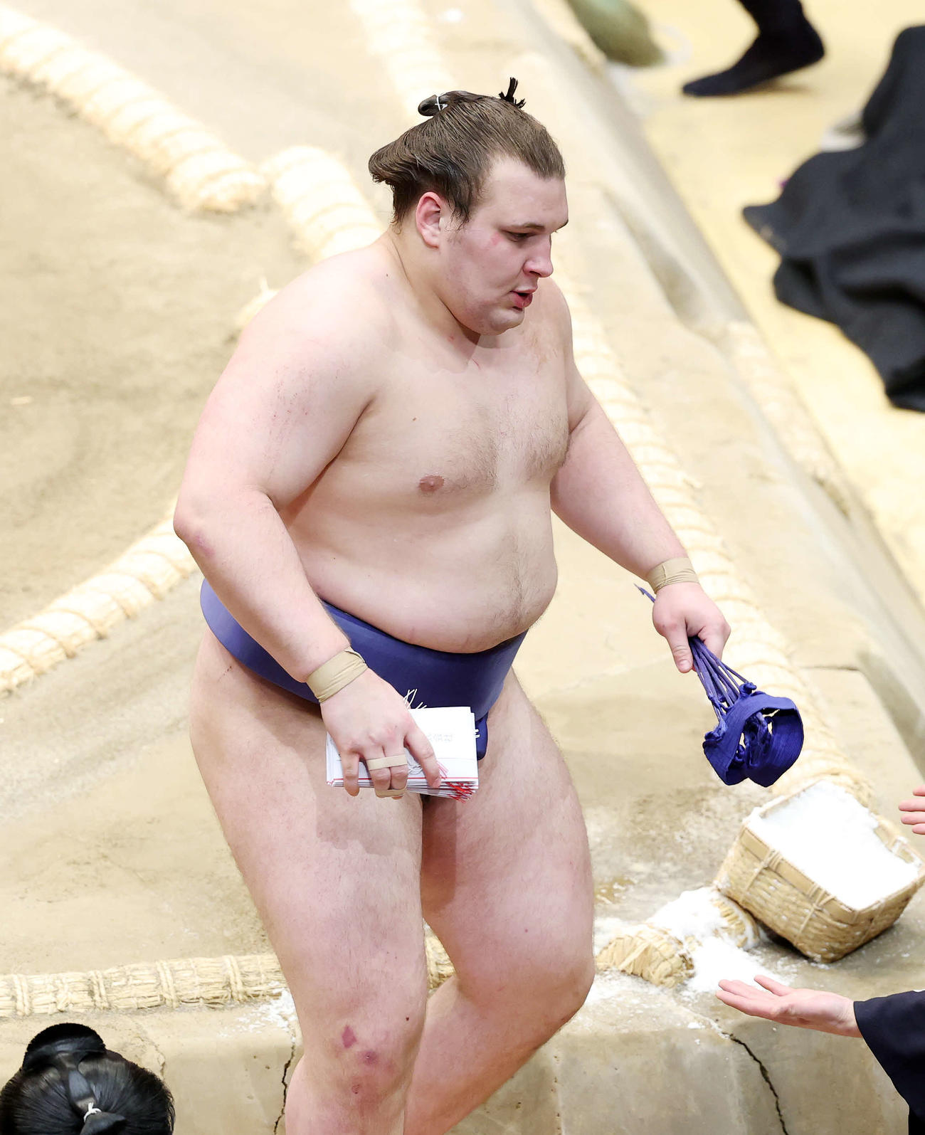 懸賞金の束を手に土俵を引き揚げる安青錦（撮影・鈴木正人）