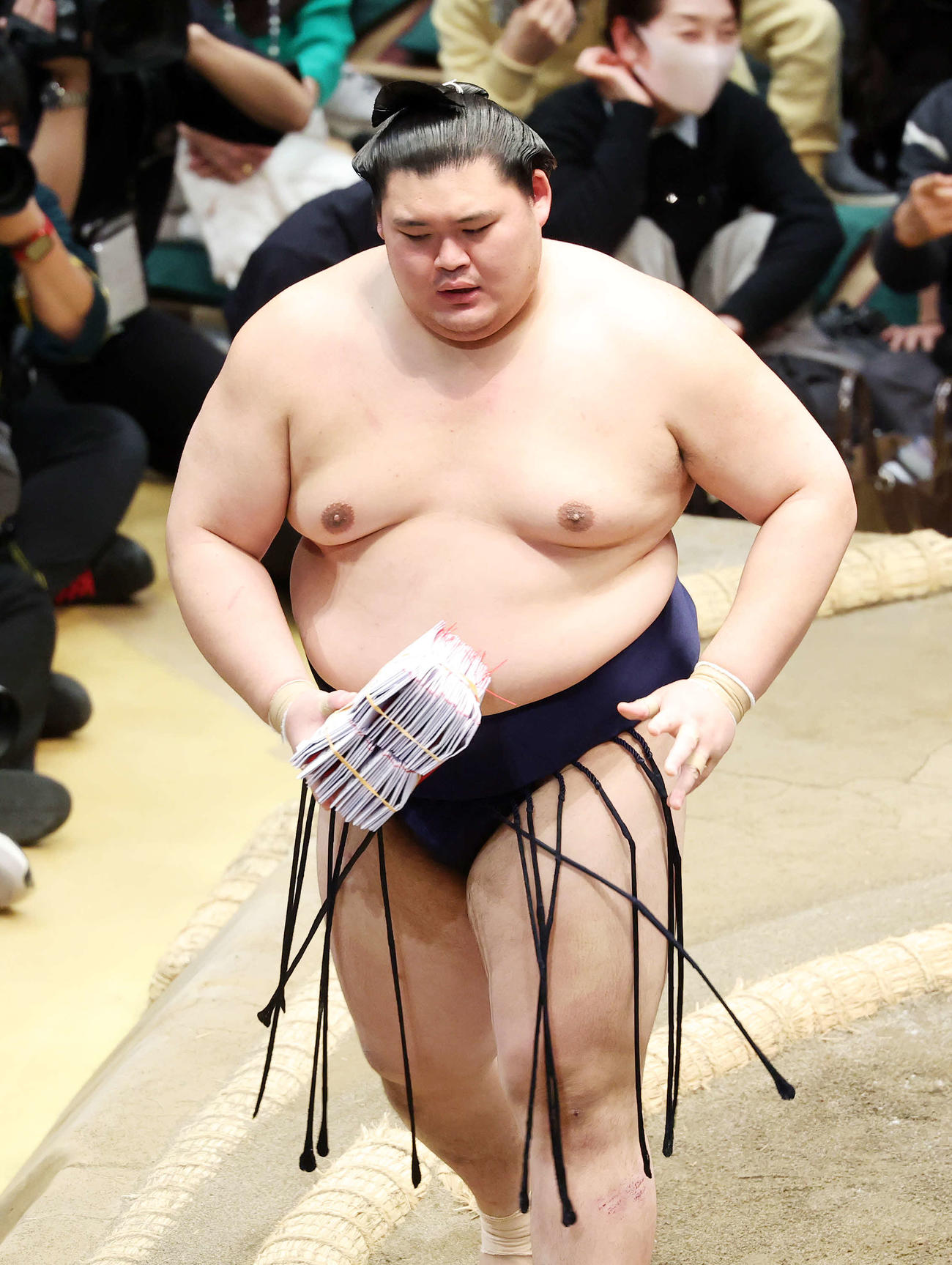 懸賞金の束を手に土俵を引き揚げる大の里（撮影・鈴木正人）