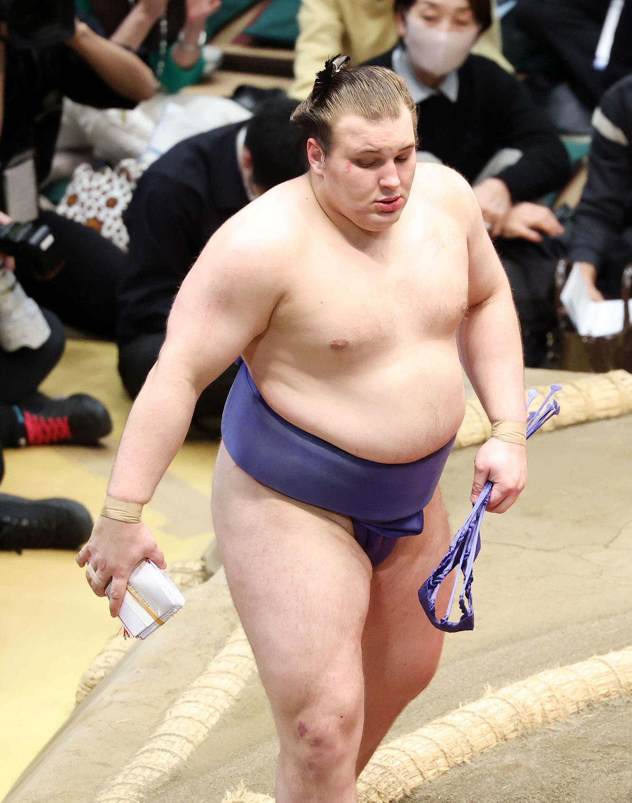 懸賞金の束を手に土俵を引き揚げる安青錦（撮影・鈴木正人）