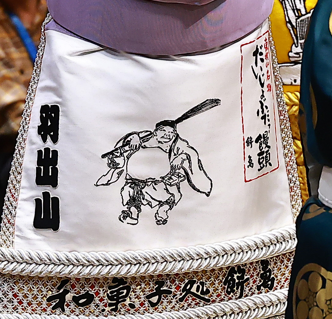 羽出山が土俵入りでつけた東村山名物、餅萬の「だいじょうぶだァー饅頭」の化粧まわし（撮影・野上伸悟）
