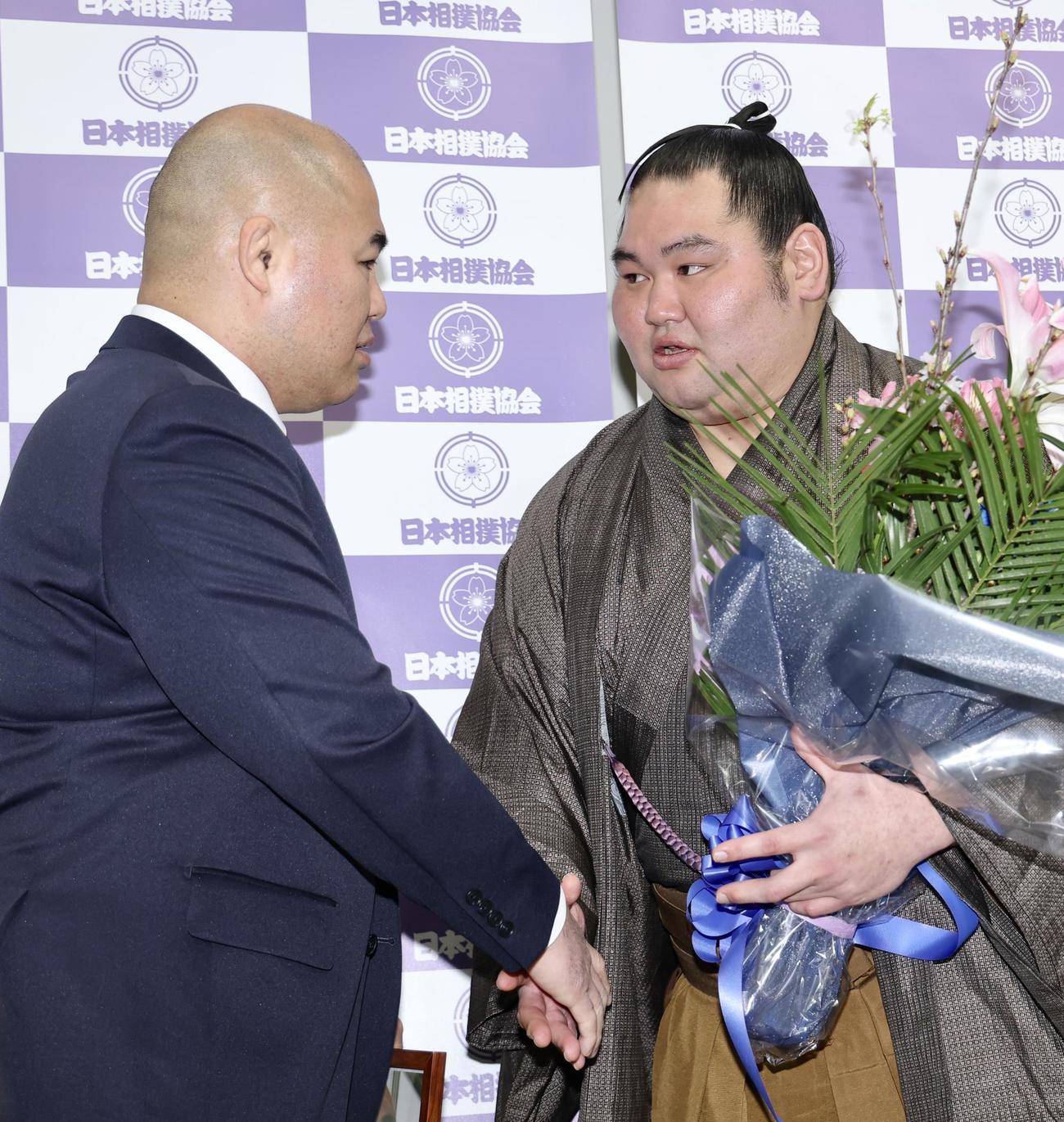千賀ノ浦親方（左）と握手を交わす大奄美（撮影・河田真司）