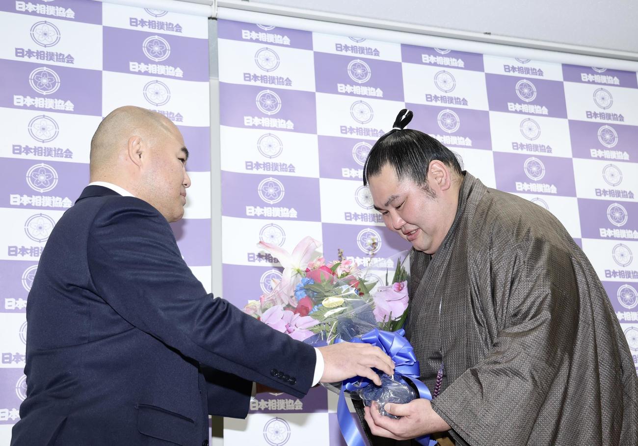 千賀ノ浦親方（左）から花束を受け取る大奄美（撮影・河田真司）