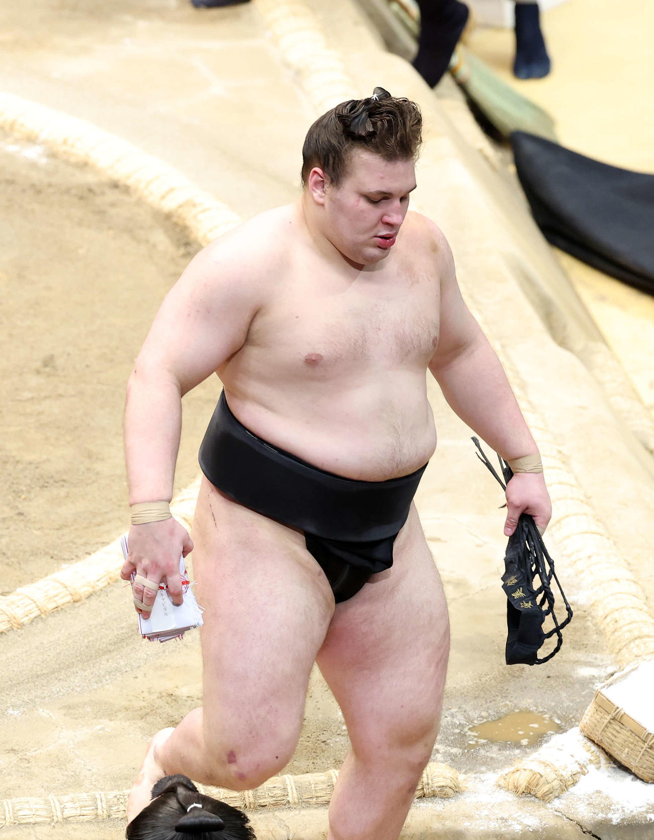 懸賞金の束を手に土俵を引き揚げる安青錦（撮影・鈴木正人）　