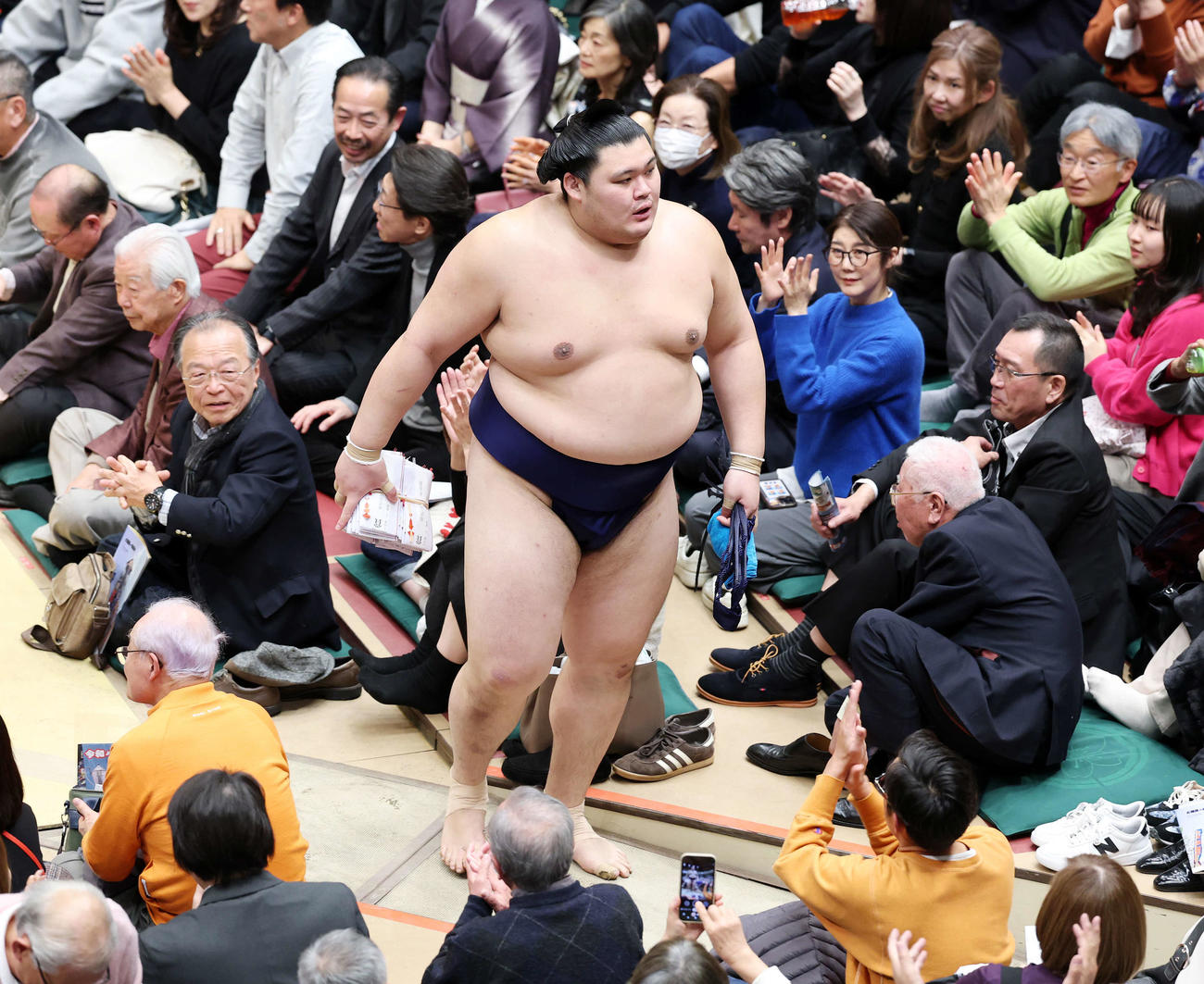 懸賞金の束を手に土俵を引き揚げる大の里（撮影・鈴木正人）　