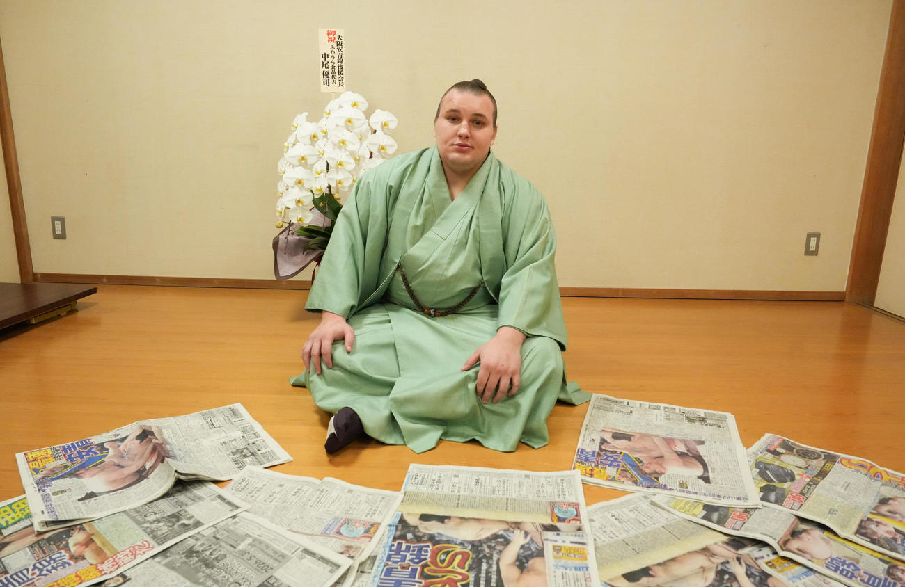 優勝を伝えた新聞各紙に囲まれる安青錦（撮影・小沢裕）